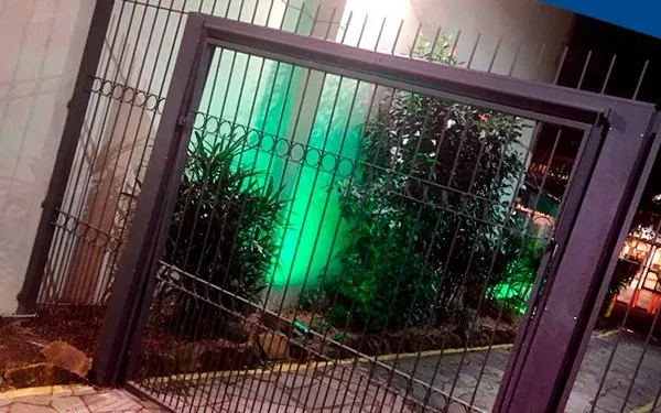 Portão social com grade, iluminado à noite